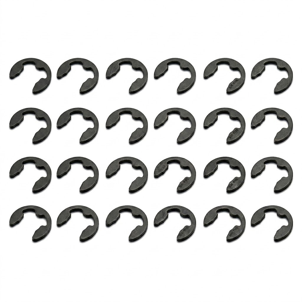 A high-resolution product photograph showing twenty-four black steel E-clips (retaining rings) neatly arranged in a grid pattern. The grid consists of four horizontal rows, each containing six identical clips oriented in the same direction. The clips are set against a crisp, solid white background, with faint, subtle shadows beneath each clip giving them a sense of depth.