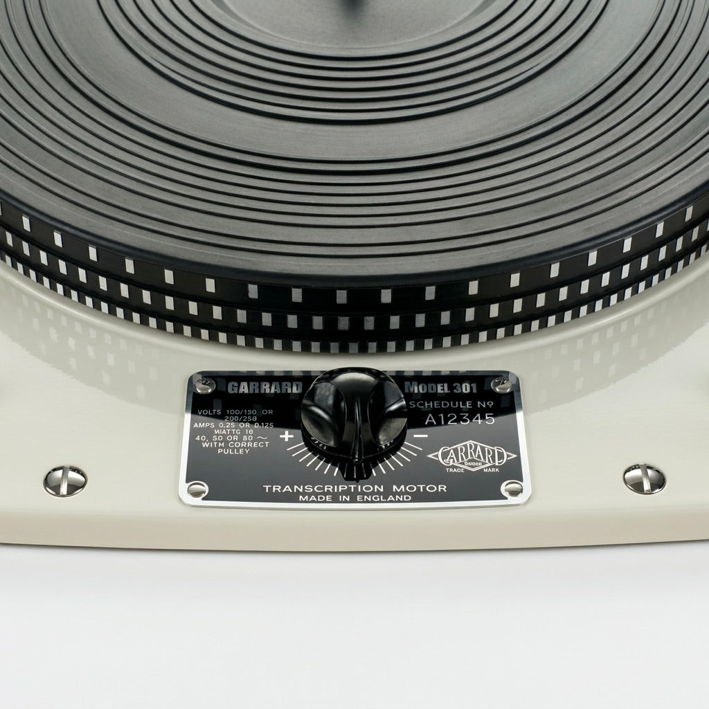 High-resolution close-up shot of a restored vintage Garrard Model 301 Schedule No 9 transcription motor turntable. The image features the iconic glossy cream-white chassis, a textured black rubber platter mat with a strobe rim pattern, and a highly polished black and silver faceplate. A central black pitch control knob sits on the faceplate alongside technical specifications and the classic Garrard logo. Two polished chrome slotted mounting bolts are visibly flush on the left and right sides of the chassis.