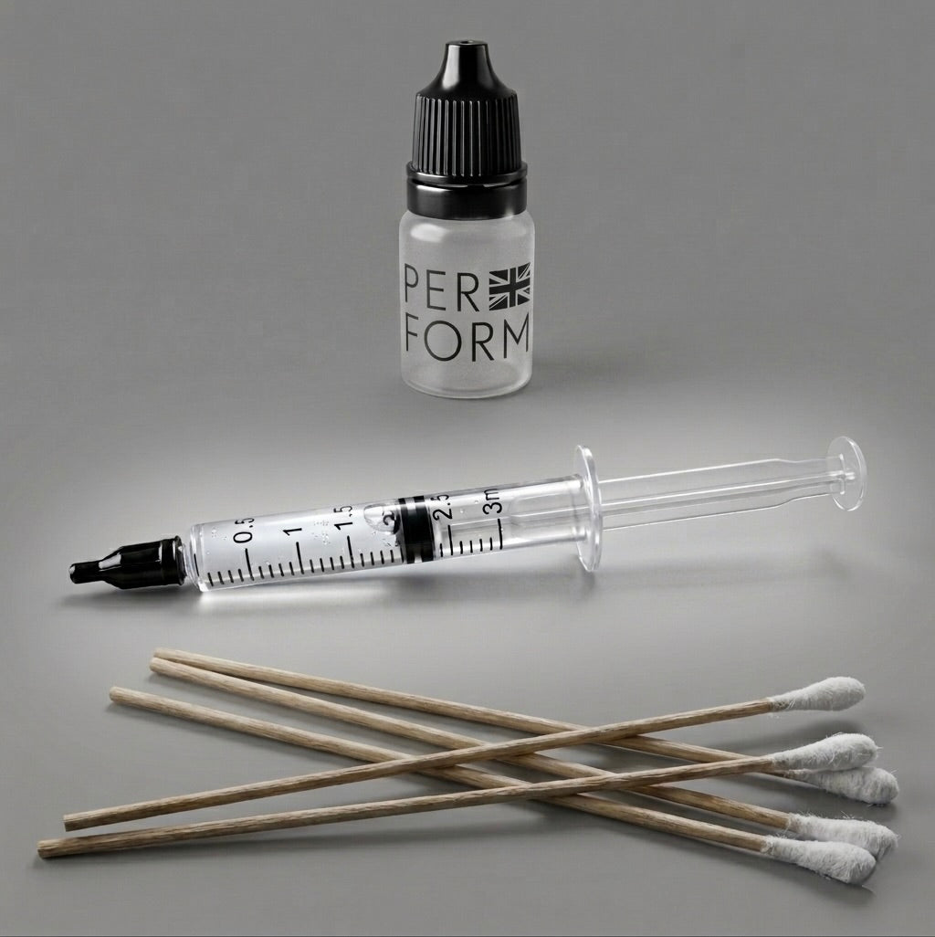 A precision liquid dispensing kit by the brand PERFORM UK for SME featuring a clear 3ml syringe with a black tip, a frosted dropper bottle with a black cap, and five long wooden-handle cotton swabs arranged on a neutral grey background.,