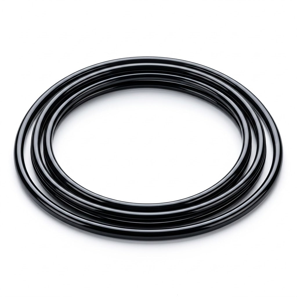 A high-resolution photograph of a glossy, jet-black round turntable drive belt, neatly coiled into multiple concentric loops. The belt rests flat against a clean, seamless bright white background, casting a soft, subtle shadow beneath it.