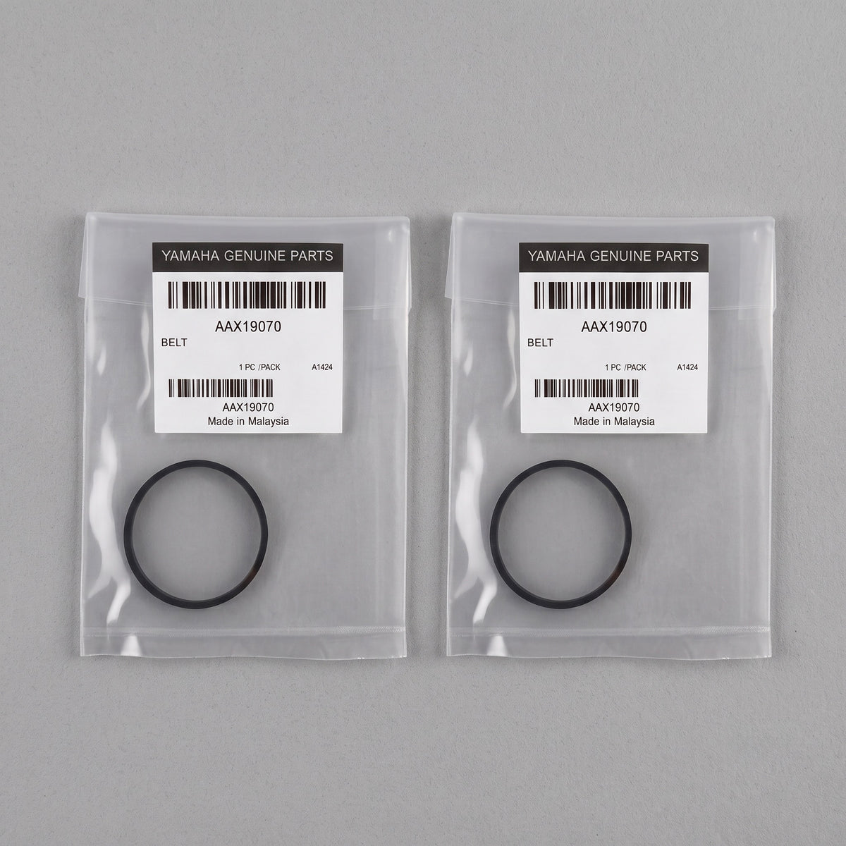 Two clear plastic bags containing black rubber belts with white Yamaha Genuine Parts labels, shown on a plain grey background.