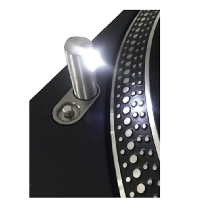 Close-up of a Technics SL-1200 series turntable featuring an upgraded, bright white LED pop-up target lamp. The cylindrical silver stylus light is in the raised position, casting a strong cool-white glow onto the edge of the spinning platter and its distinctive strobe dots. The sleek black finish of the turntable deck provides a high-contrast background for the illuminated LED.