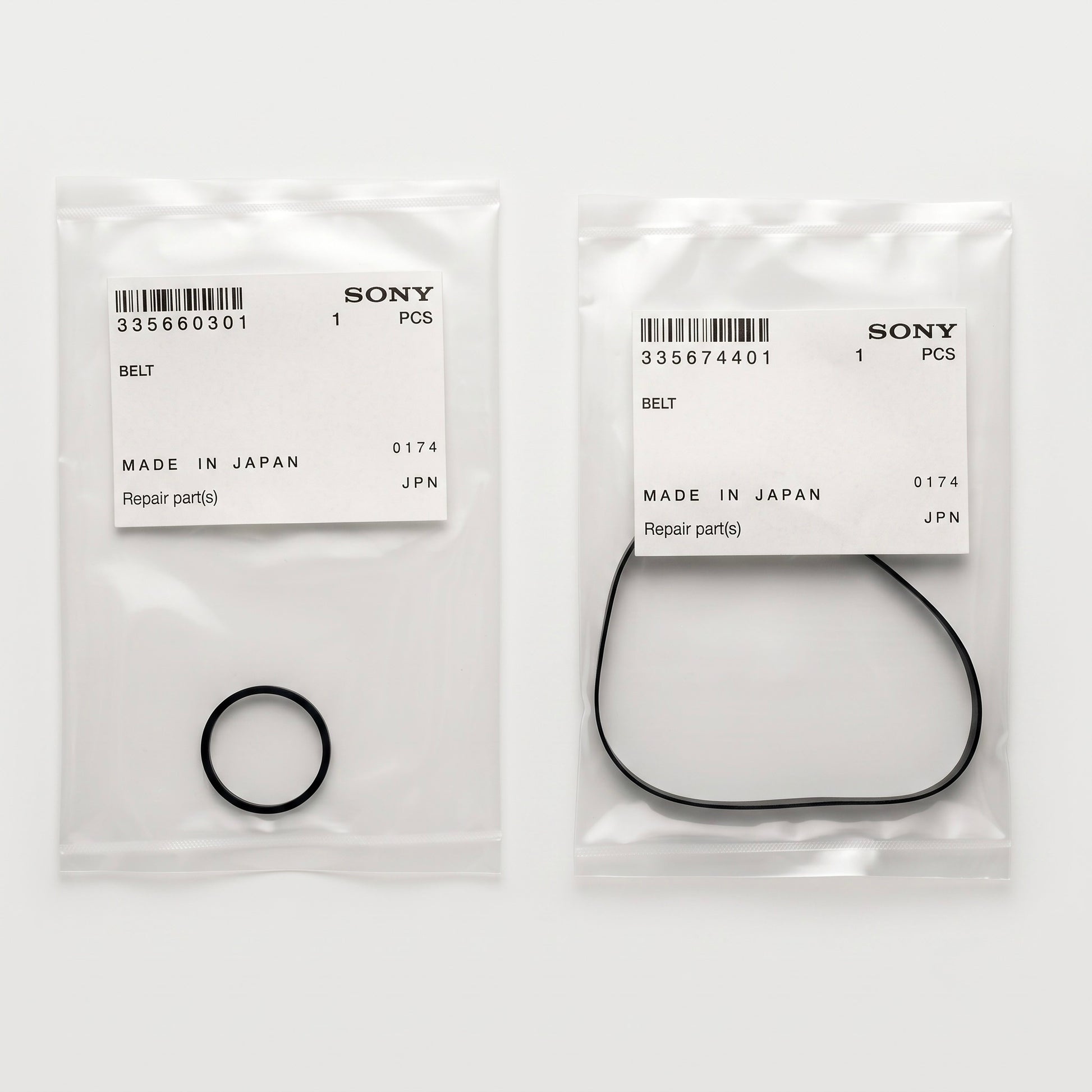 A top-down product photograph shows two separate, transparent plastic parts bags lying side-by-side on a plain white surface. Each bag contains a genuine Sony replacement belt and features an official white paper label stuck to the front.