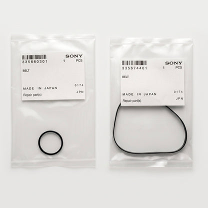 A top-down product photograph shows two separate, transparent plastic parts bags lying side-by-side on a plain white surface. Each bag contains a genuine Sony replacement belt and features an official white paper label stuck to the front.