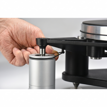 Close-up of a hand installing a black AVID HIFI turntable lateral suspension band onto the sub-chassis and silver pillar mechanism of a high-end vinyl turntable setup.