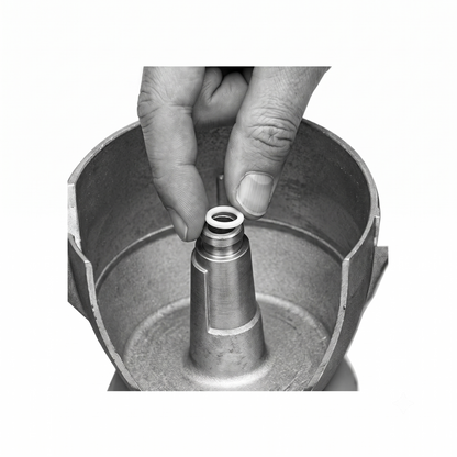 A close-up black-and-white photo of a person's hand inserting a small O-ring into a cylindrical metal component inside a larger metal container.