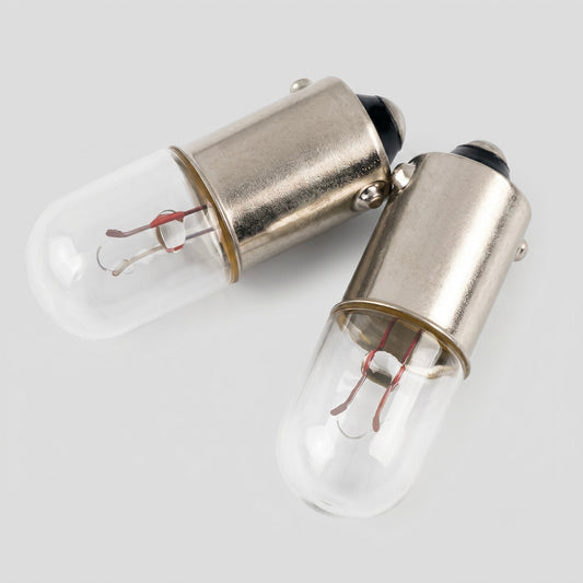Two vintage-style T47 miniature pilot light bulbs with cylindrical clear glass envelopes, showing the internal wire filaments and supports, paired with metal bayonet bases and set against a solid white background.