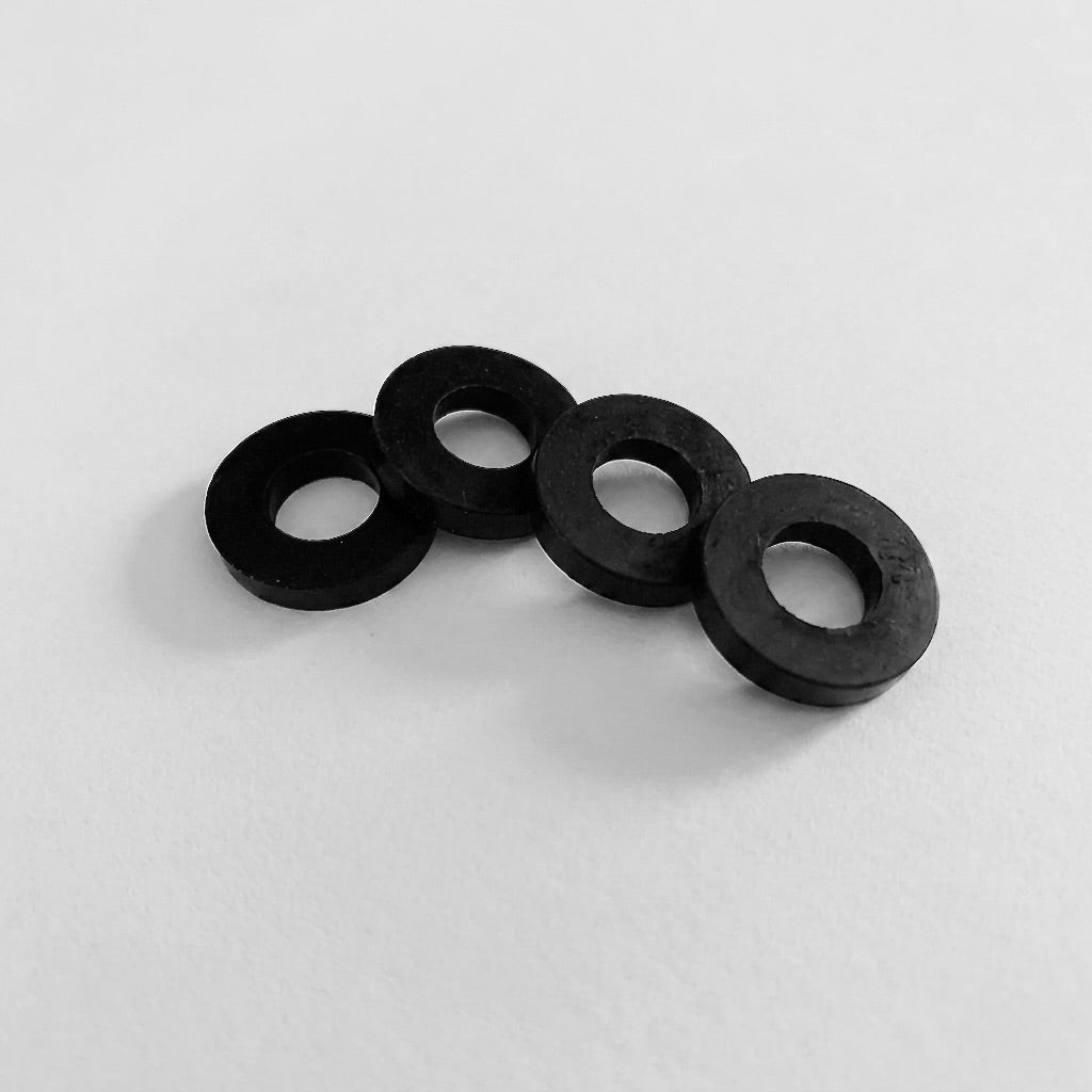 Four black rubber washers on a white background