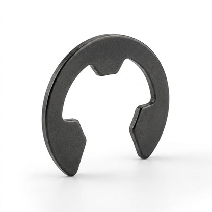 A dark grey metal E-clip circlip standing upright on a white surface, showing its three internal prongs used for securing mechanical shafts.