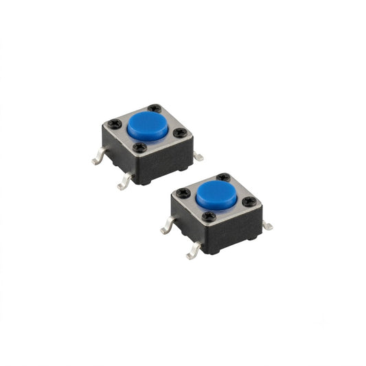 An isolated studio shot of a two-pack of upgraded power switches for a Gtech handheld vacuum, arranged diagonally against a seamless white background. Each component is a small, square tactile micro-switch featuring a black plastic housing body, a metallic silver top plate secured by four tiny rivets, and a vibrant blue circular push-button in the center. Four gull-wing shaped metallic solder leads extend from the sides for surface-mount installation.