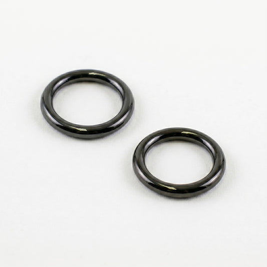 Two glossy, dark black rubber O-rings resting diagonally on a clean, solid white background, showing the shiny surface texture of the Marantz TT-15S1 turntable counterweight seals.