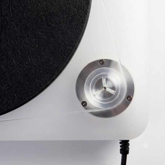 A top-down close-up shot of a clear silicone drive belt wrapped around the metallic motor pulley and the outer edge of a white turntable platter.