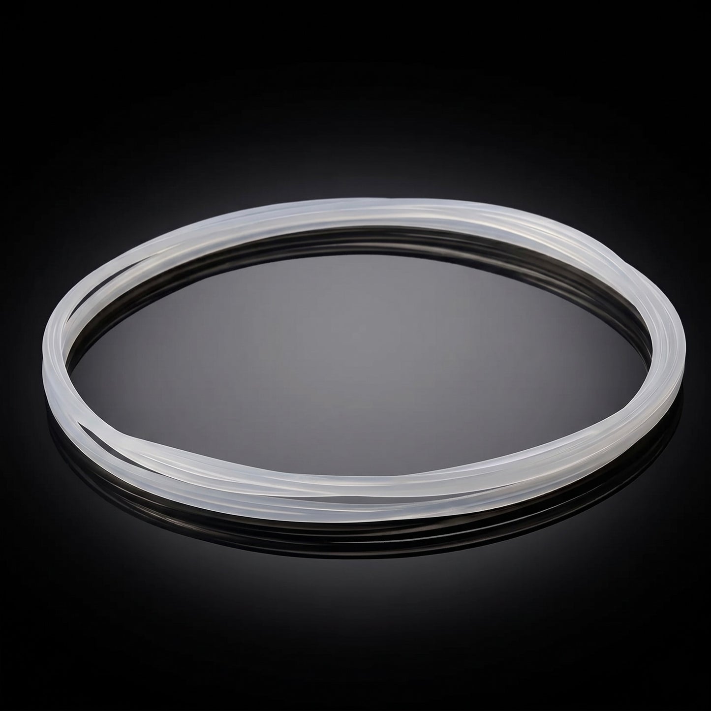 A translucent, white silicone turntable drive belt resting in an oval shape on a reflective, shiny black surface with a dark background.