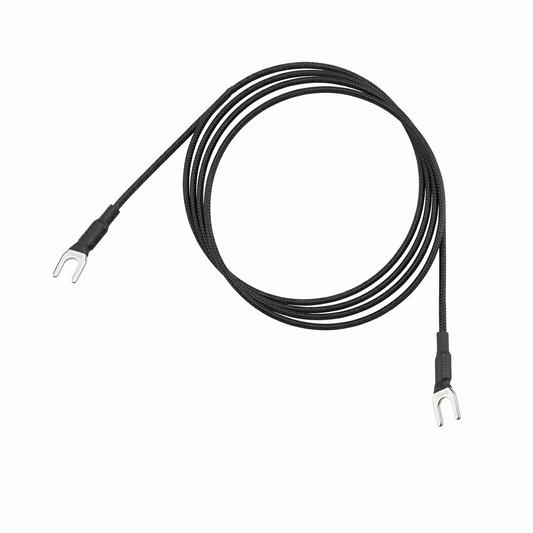 A Pro-Ject Connect it turntable earthing ground wire coiled into a neat circle against a plain white background. The black cable features a textured, braided sleeve and terminates at both ends with silver u-shaped spade connectors wrapped in black heat-shrink tubing.