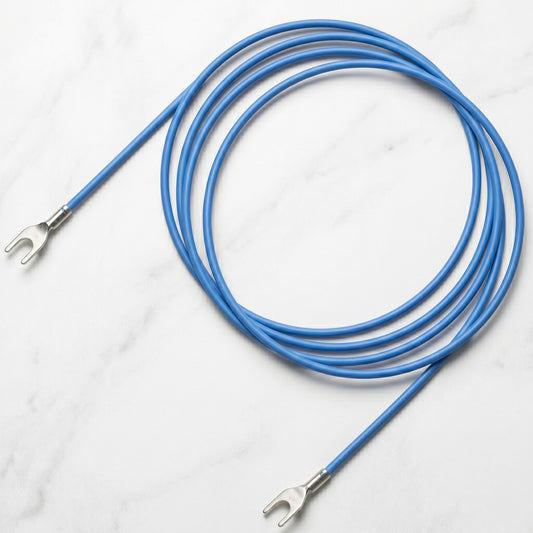 An overhead product shot of a bright blue, single-core turntable ground wire, shown coiled on a light grey and white marble surface, features two pre-terminated silver spade/fork connectors, identical to the cable in "Pro-Ject Turntable Earthing Ground Lead (Yellow) By Perform.