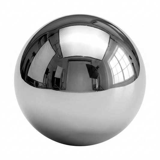 An isolated, highly reflective chrome steel ball bearing sits centered against a solid white background. The upper half of the sphere mirrors a black-and-white photography studio setup, featuring softboxes, light stands, and a large window casting realistic highlights and reflections across its polished, metallic surface.