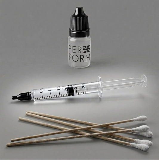 A precision liquid dispensing kit by the brand PERFORM UK for SME featuring a clear 3ml syringe with a black tip, a frosted dropper bottle with a black cap, and five long wooden-handle cotton swabs arranged on a neutral grey background.,