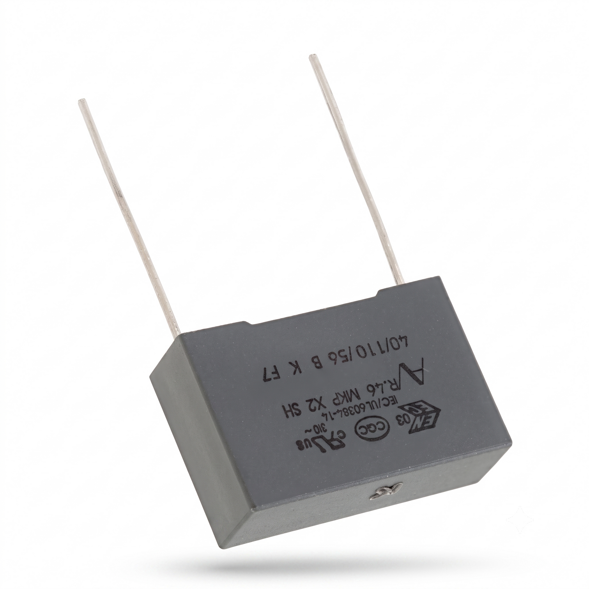 A gray rectangular electronic capacitor with two thin metal leads, shown at an angle on a white background with a soft shadow.