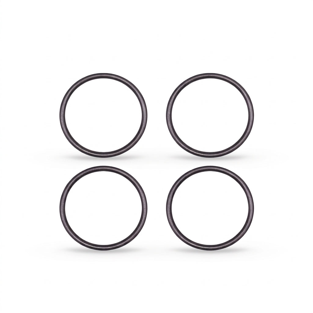 High-resolution, clean studio shot displaying four identical black rubber O-rings arranged in a neat two-by-two grid against a solid white background. Each circular ring features a smooth, rounded profile with subtle metallic or semi-gloss highlights that give them a three-dimensional appearance. Soft, faint shadows are cast directly beneath each ring, grounding them on the surface.