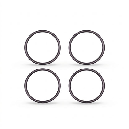 High-resolution, clean studio shot displaying four identical black rubber O-rings arranged in a neat two-by-two grid against a solid white background. Each circular ring features a smooth, rounded profile with subtle metallic or semi-gloss highlights that give them a three-dimensional appearance. Soft, faint shadows are cast directly beneath each ring, grounding them on the surface.