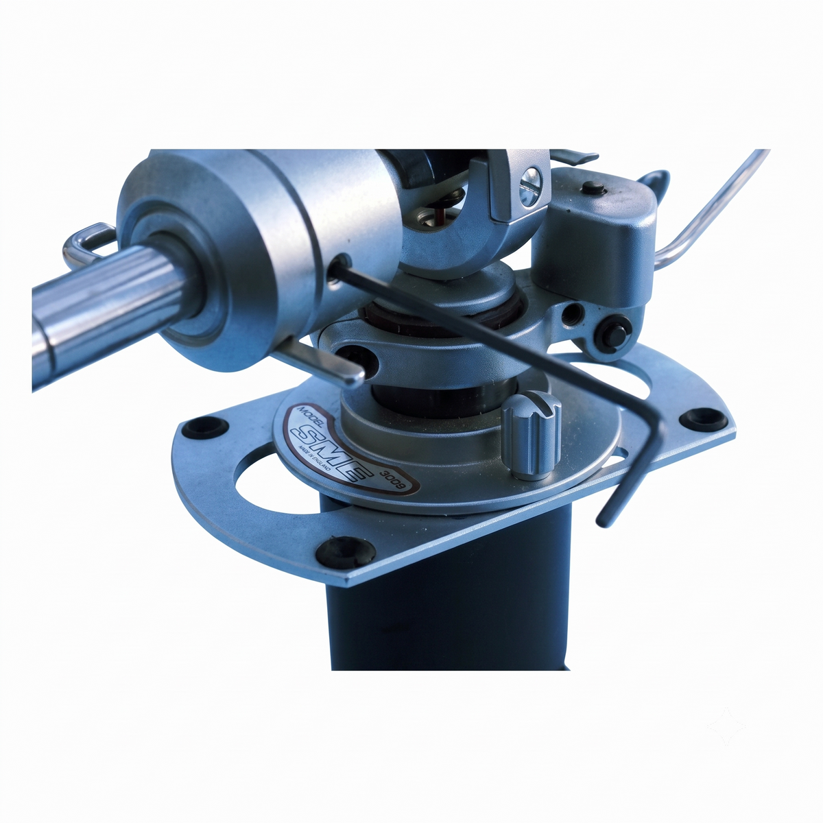 Close-up of an SME tonearm assembly with a circular mounting plate, cylindrical components, and a small Allen wrench, photographed on a plain white background.