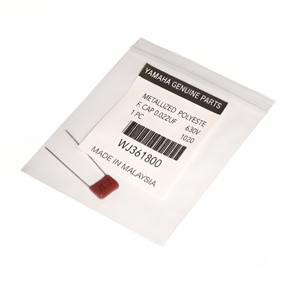 A close-up photograph of a small electronic component in a clear plastic resealable bag on a light-colored surface. The bag contains a brown metallized polyester film capacitor with two long metal leads extending from its body. A white label is affixed to the bag, featuring the following printed text: YAMAHA GENUINE PARTS at the top in a black bar, below which reads METALLIZED POLYESTE, F. CAP 0.022UF, 630V, 1 PC, 1020.